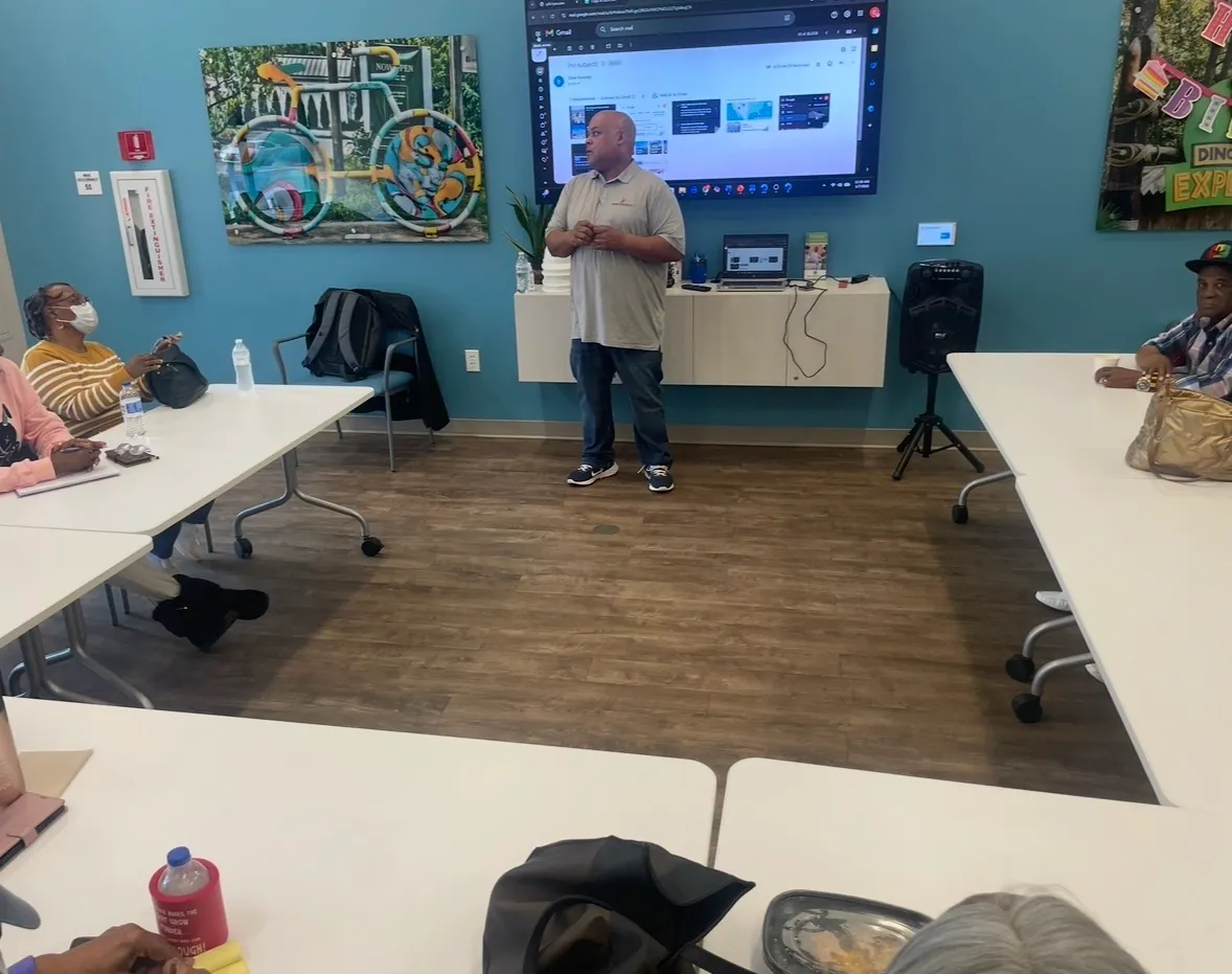 Chet Beasley teaching a class, standing at a screen while participants follow along at tables.